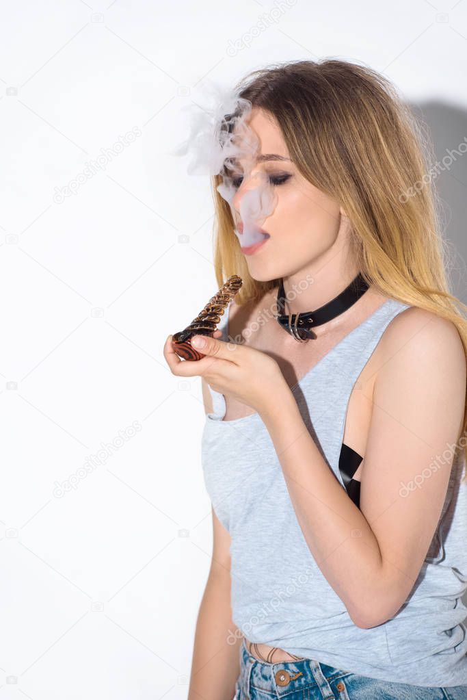 attractive young woman smoking cannabis with pipe on white