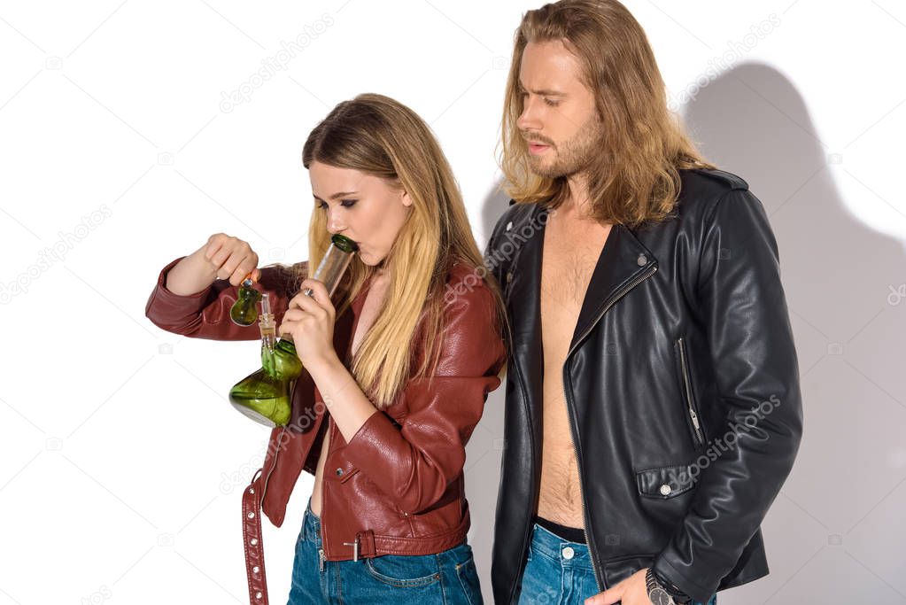 young addicted couple with water pipe smoking marijuana on white