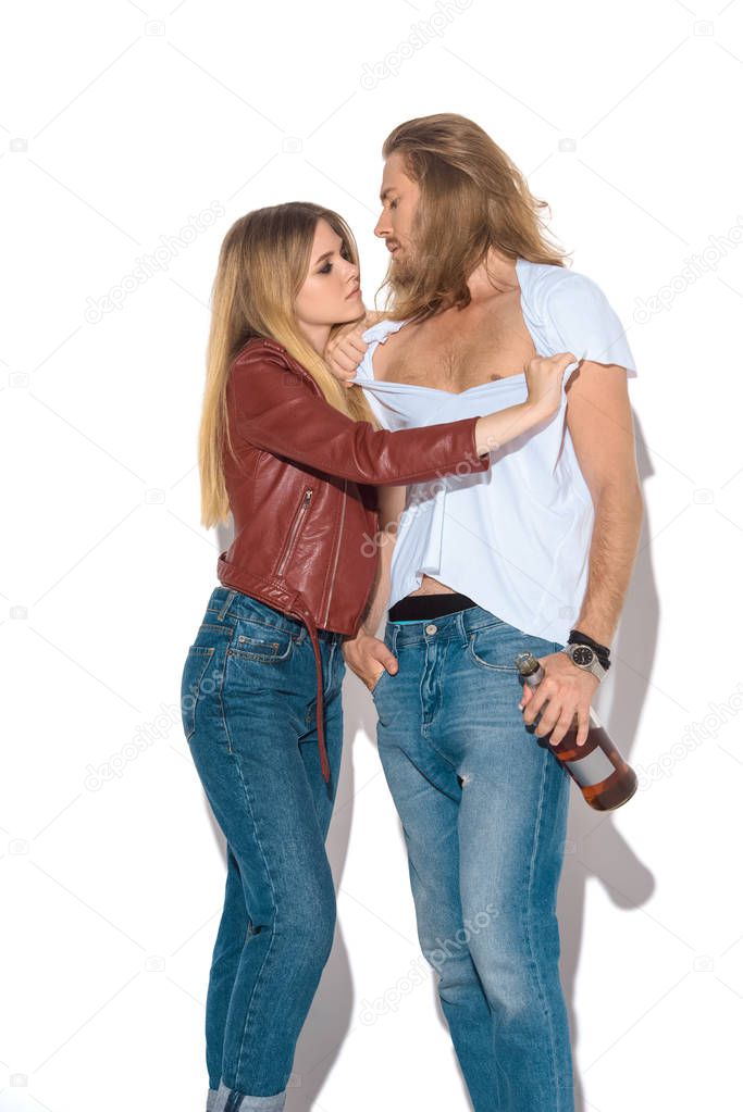 passionate young drunk couple with bottle of rum on white