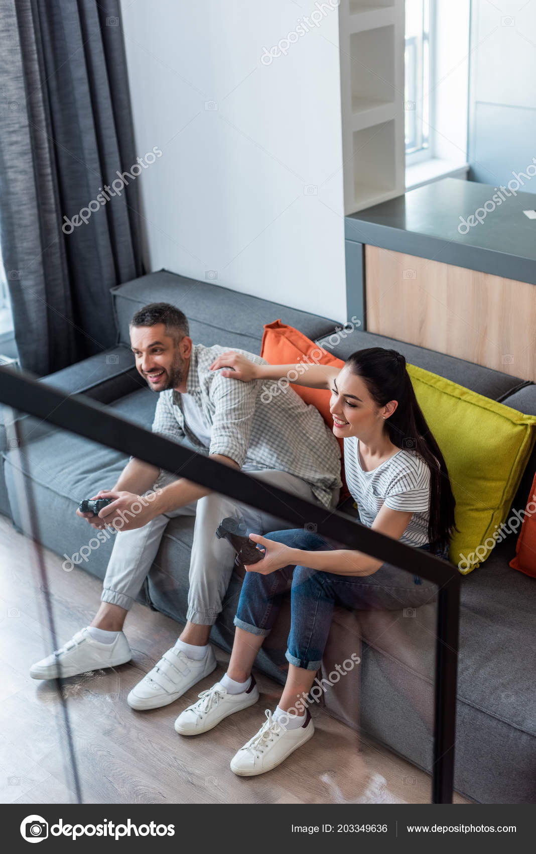 Happy Couple Sitting On The Sofa Playing Video Games Using