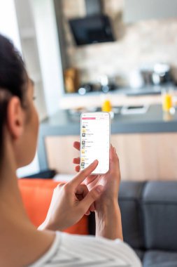 selective focus of woman using smartphone in kitchen clipart