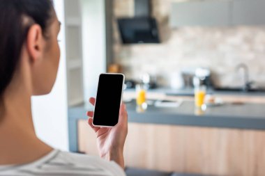 seçici odak smartphone boş ekran ile mutfakta elinde tutan kadın