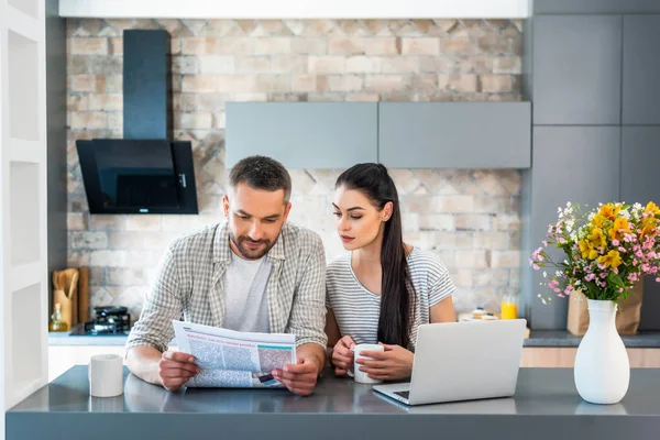 Porträtt Gift Par Läsa Tidningen Tillsammans Vid Disken Med Laptop — Stockfoto