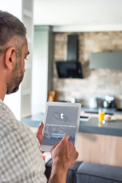 キッチンの画面で Tumblr のロゴとデジタル タブレットを使用している人の選択と集中 — ストック写真