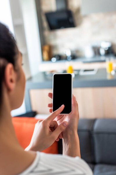 selective focus of woman using smartphone with blank screen in kitchen