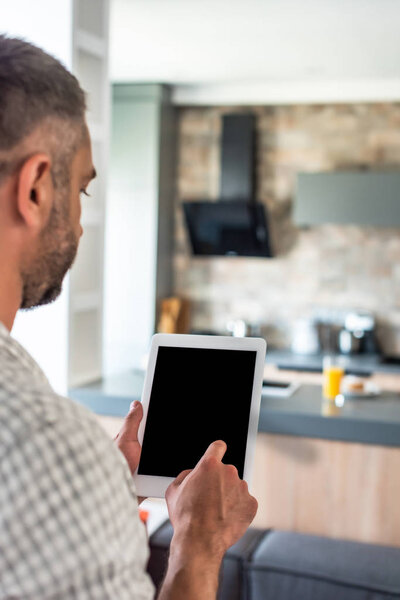selective focus of man using tablet with blank screen in kitchen