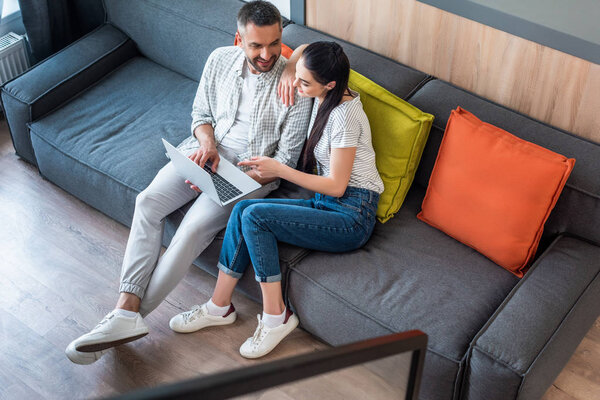 high angle view of couple using laptop together while resting on sofa at home