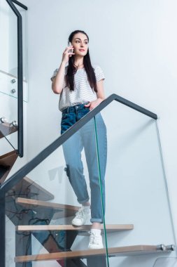 çekici kadın merdivenlerde evde dururken smartphone üzerinde söz düşük açılı görünümü