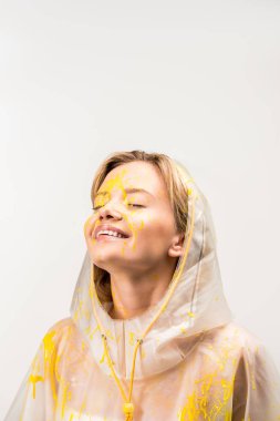 yağmurluk mutlu güzel kadın ile sarı boya ayakta beyaz izole kapalı gözlerle boyalı 