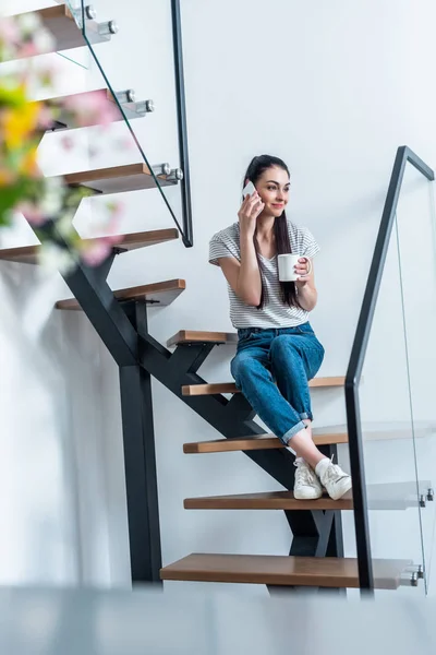 Woman Cup Coffee Hand Talking Smartphone While Sitting Stairs Home — Free Stock Photo