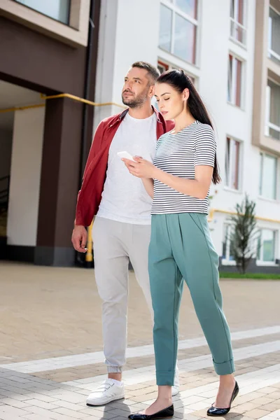 Frau Benutzt Smartphone Während Sie Mit Mann Auf Der Straße — Stockfoto