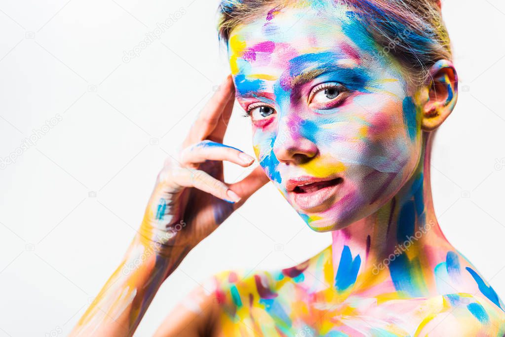 attractive girl with colorful bright body art touching head and looking at camera isolated on white 