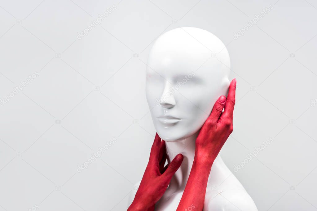 cropped image of woman in red paint touching mannequin neck and face isolated on white