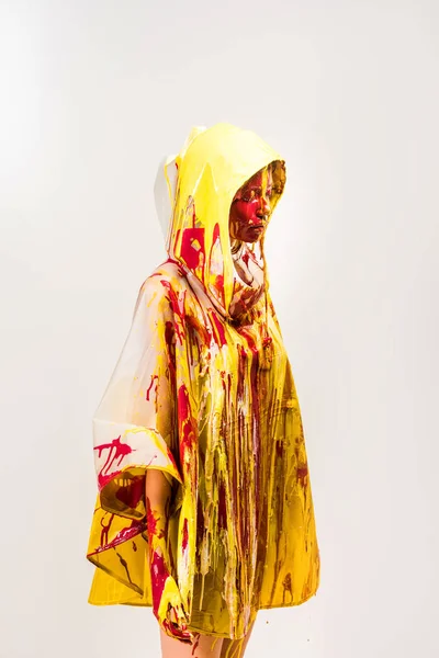 美丽的女人在雨衣上画的黄色和红色的油漆站在罩上的白色隔离 — 图库照片