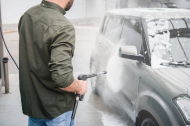 cropped image of man cleaning car from foam at car wash with high pressure water jet clipart