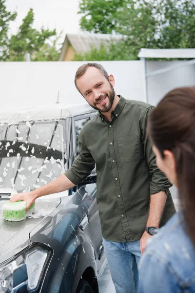 縫いぐるみと泡洗車で笑顔のカップル清掃車 — ストック写真