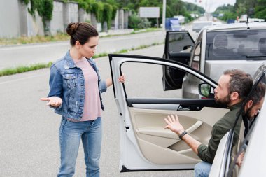 male and female drivers quarreling and gesturing on road after car accident clipart