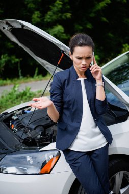 angry businesswoman talking by smartphone near broken car clipart