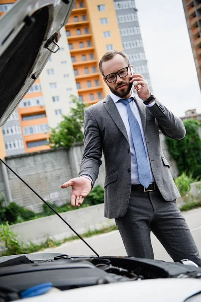 Stilig Affärsman Talar Smartphone Nära Trasiga Bil Med Öppna Huven — Stockfoto