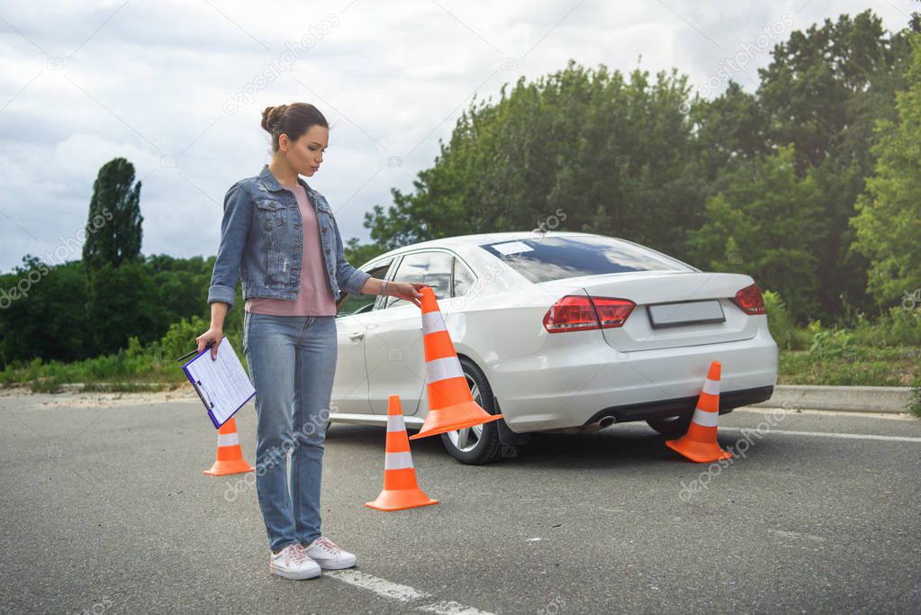 driver holding car insurance and putting traffic cones on road