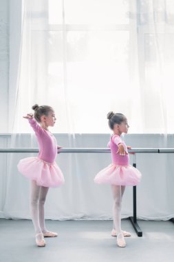 side view of cute small ballet dancers exercising in ballet school clipart