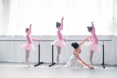 side view of young ballet teacher exercising with kids in ballet school  clipart
