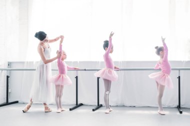 side view of ballet teacher exercising with children in ballet school  clipart