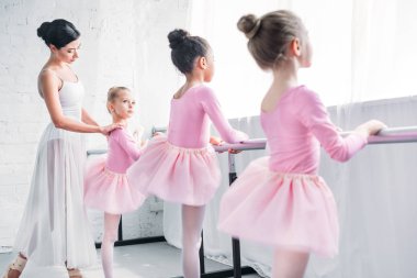 cute little kids in tutu skirts exercising with teacher in ballet school clipart