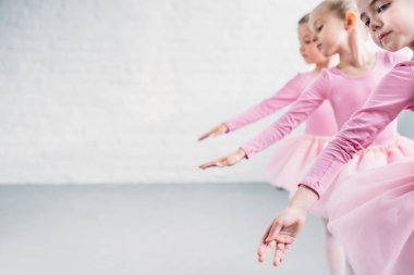side view of graceful little ballerinas dancing together in ballet school clipart