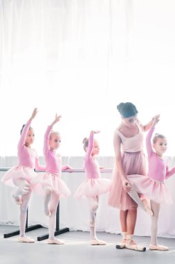 Genç kadın sevimli çocuklara bale okulunda dans öğretim 