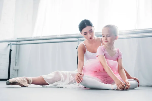 young ballet teacher training with cute little child in ballet school