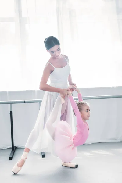 Jeune Professeur Ballet Aidant Petit Élève Étirer Pendant Formation École — Photo gratuite