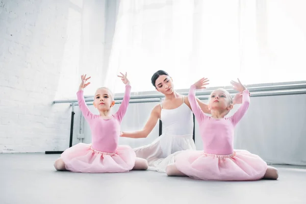 学校でバレエの練習チュチュ スカートのかわいい子供を見て若いバレエ教師 — ストック写真