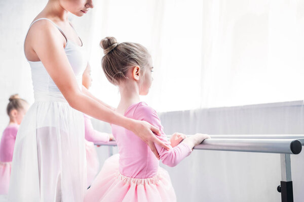 cropped shot of ballet teacher exercising with kids in ballet school