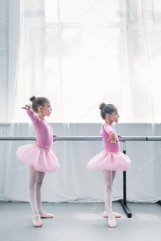 side view of cute small ballet dancers exercising in ballet school