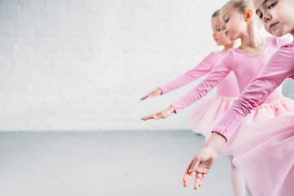 side view of graceful little ballerinas dancing together in ballet school