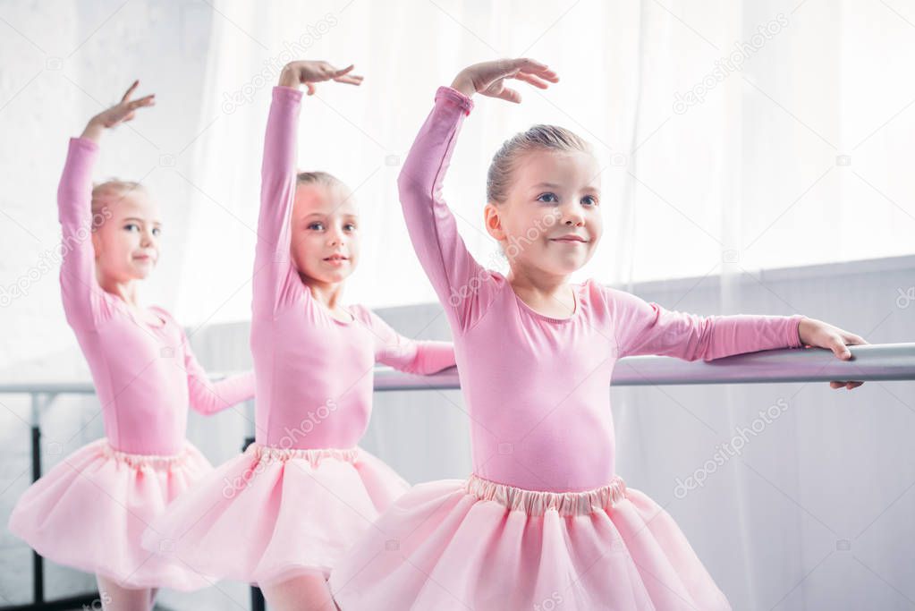 adorable smiling children in pink tutu skirts dancing in ballet studio 
