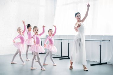 young teacher practicing ballet with adorable kids in pink tutu skirts clipart