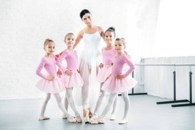 ballet teacher with cute little ballerinas smiling at camera in ballet school clipart