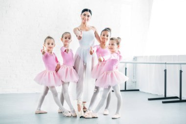 little ballerinas and ballet teacher showing thumbs up and smiling at camera in ballet school clipart