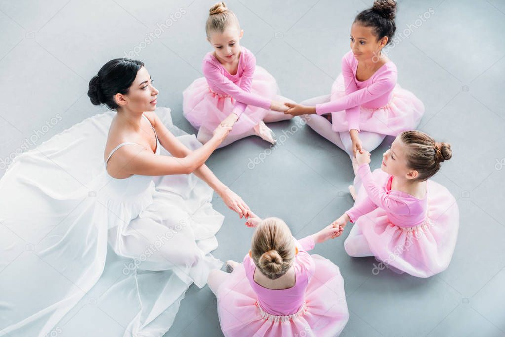 high angle view of little ballerinas and ballet teacher exercising together in ballet school