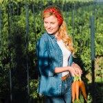 Attractive farmer holding organic carrots in field at farm