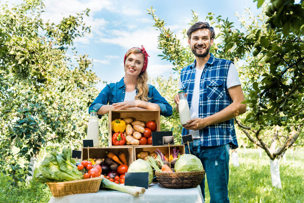 smiling couple of farmers looking at camera at farmer market