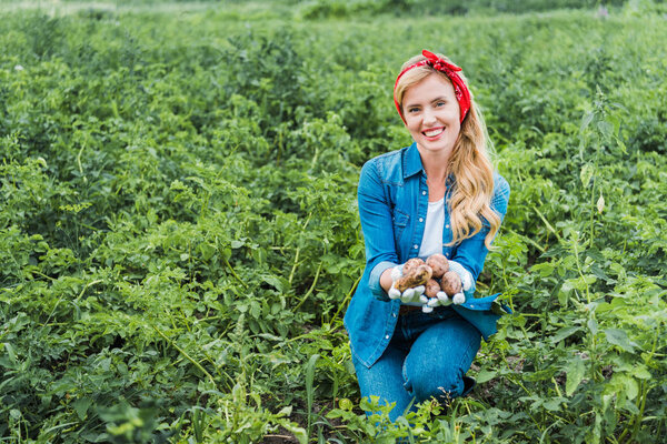 attractive farmer showing ripe potatoes in field at farm