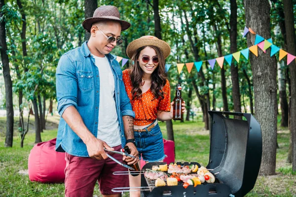 Leende Kvinna Med Tittar Afrikanska Amerikanska Pojkvän Laga Mat Grillen — Stockfoto