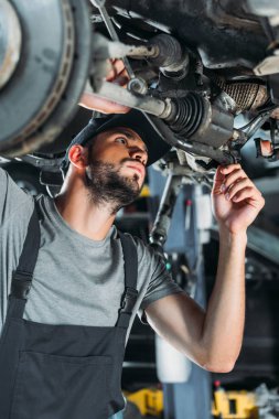 professional engineer in overalls repairing car in mechanic shop clipart