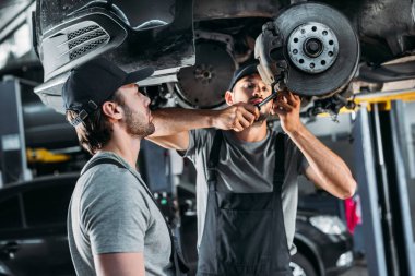 professional mechanics repairing car without wheel in auto repair shop