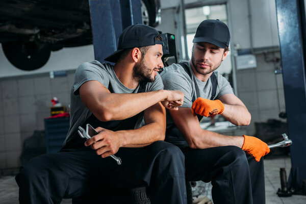 manual workers bumping fists together in mechanic shop
