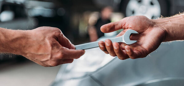 cropped view of mechanics holding wrench in auto repair shop