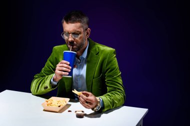 abur cubur ile masada oturan mavi zemin ile soda içme kadife ceketli şık adamı